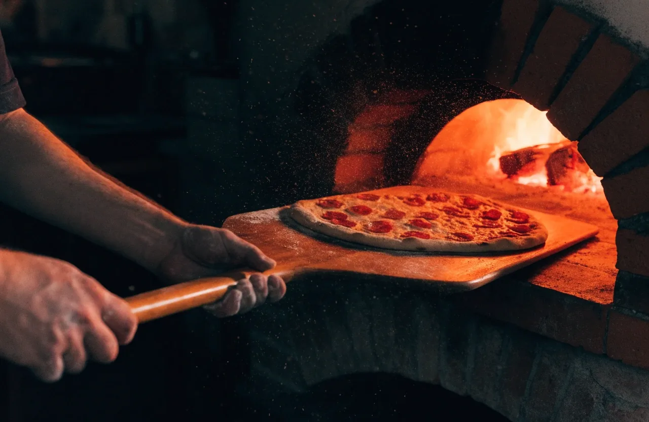 Glowing oven mouth in a dark pizzeria with warm light