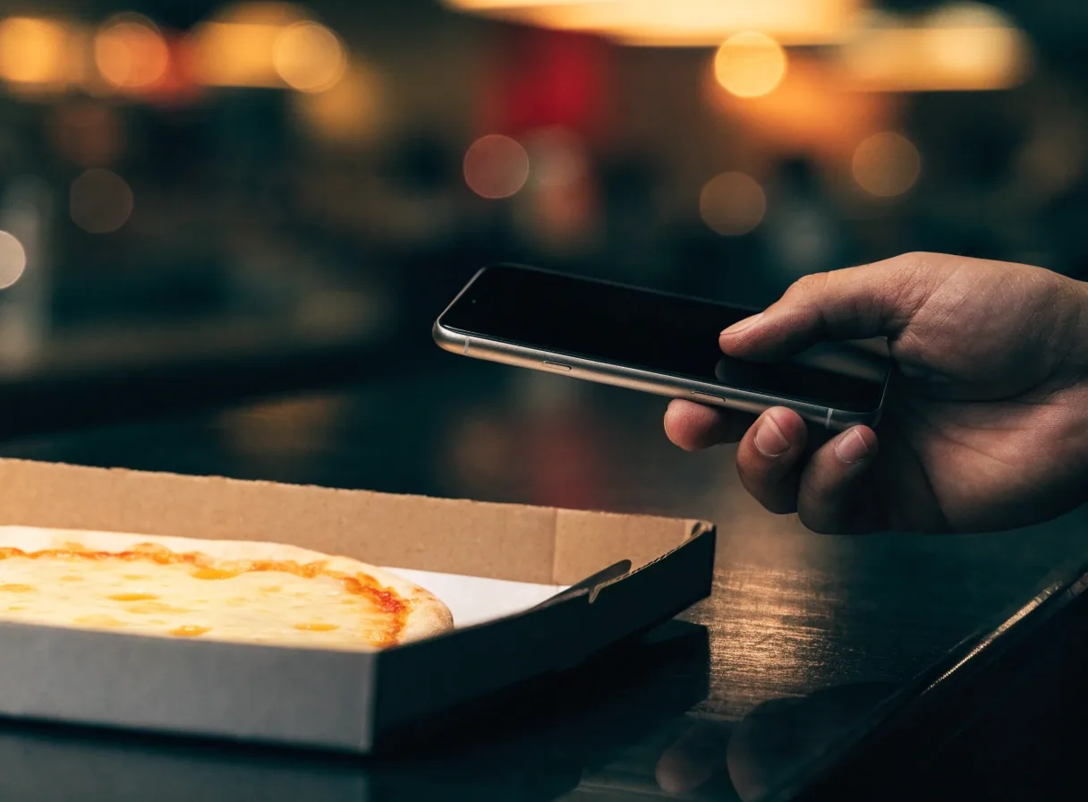 Phone held over a dark pizzeria counter